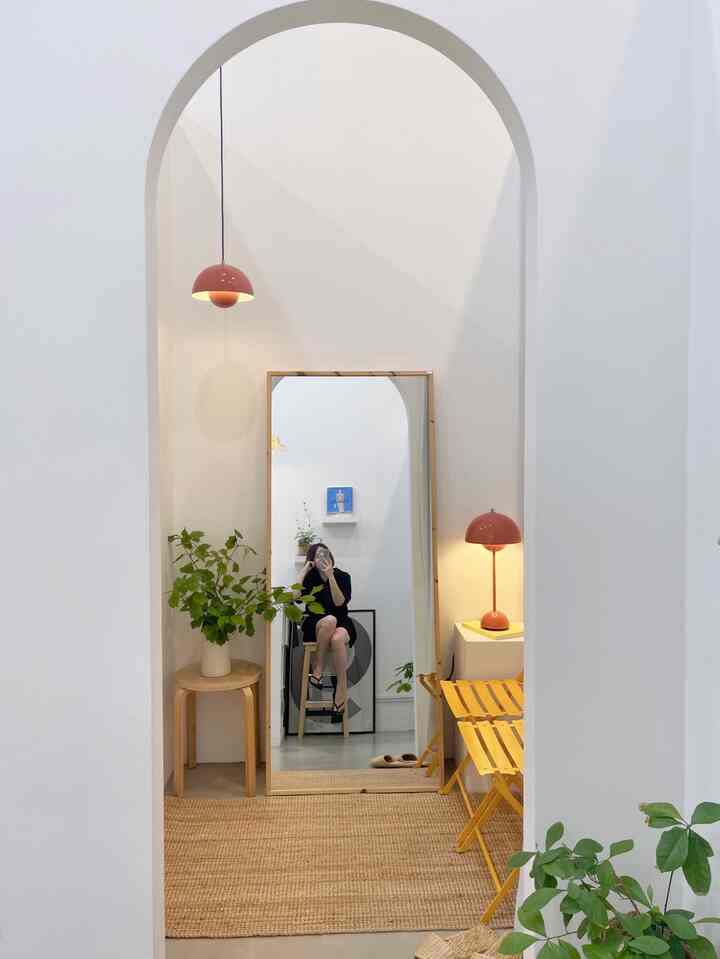 Natural tone arched entrance space featuring a large mirror, red pendant lamp, and woven natural fiber rug with simple interior style