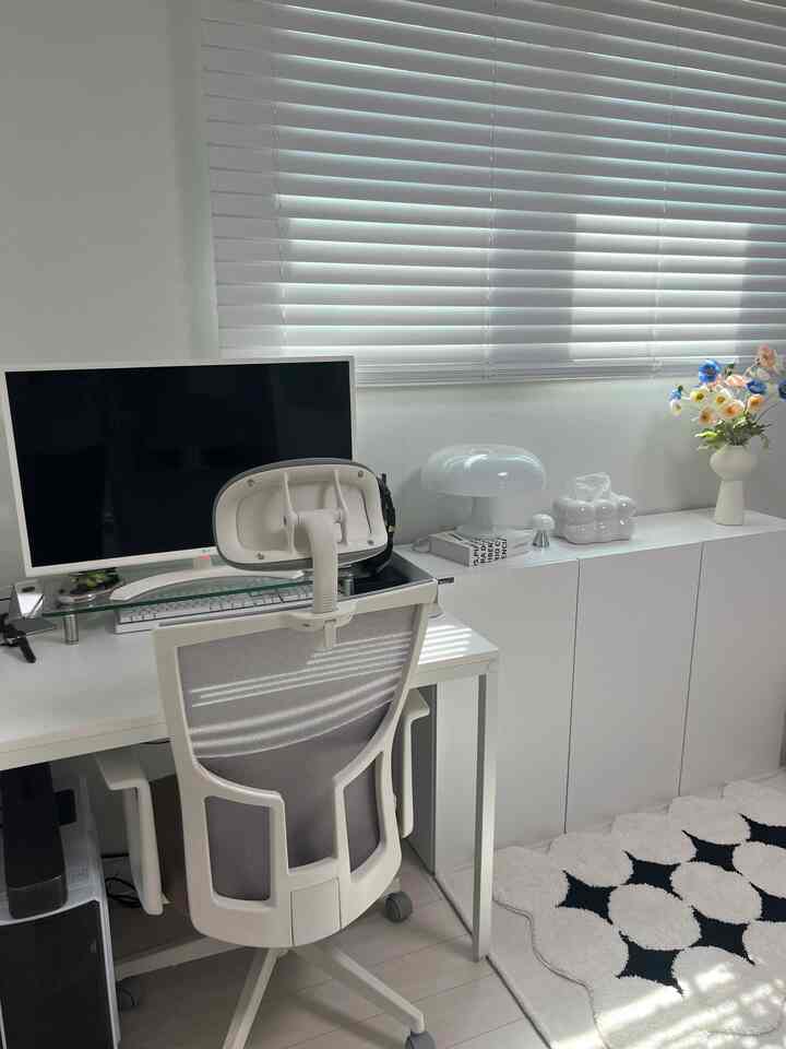 White and gray toned study featuring computer desk, ergonomic chair, white storage cabinet, and modern lamp in a clean home office setup