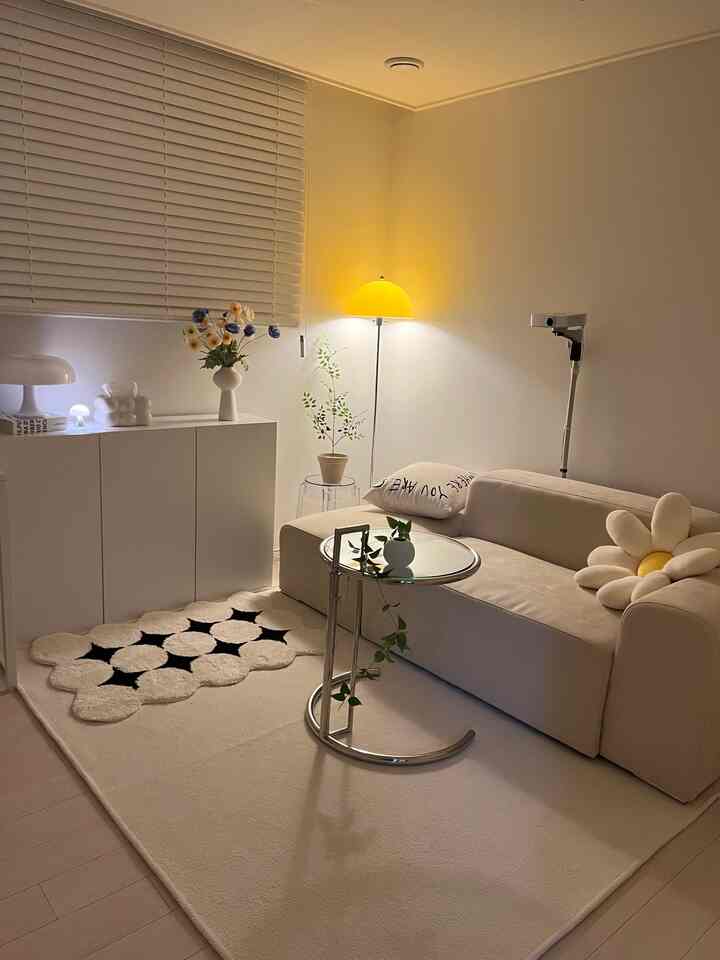 A cozy home cinema living room in soft beige and white tones, featuring a simple modern two-seat sofa, side table, and floor lamp