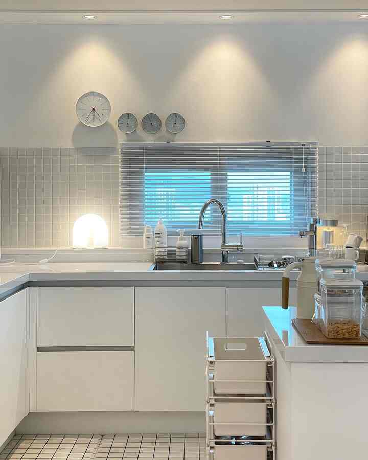 Bright white-toned kitchen featuring a sink and tidy storage bins in a simple space