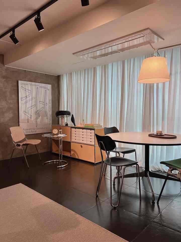 Modern home office and dining space in white and black tones, featuring a round dining table, metal chairs, and chiffon curtains creating a clean and stable atmosphere