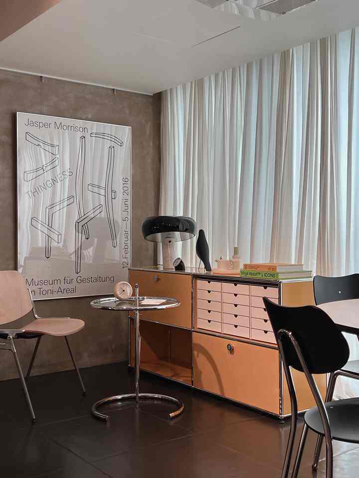 Industrial style workspace with white curtains and brown storage unit, featuring minimalist table lamp and clock as key accents