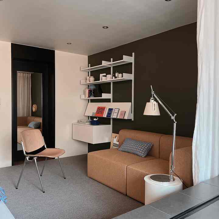 Warm brown and white toned living room featuring a modern sofa, armchair, and wall shelves creating a cozy atmosphere