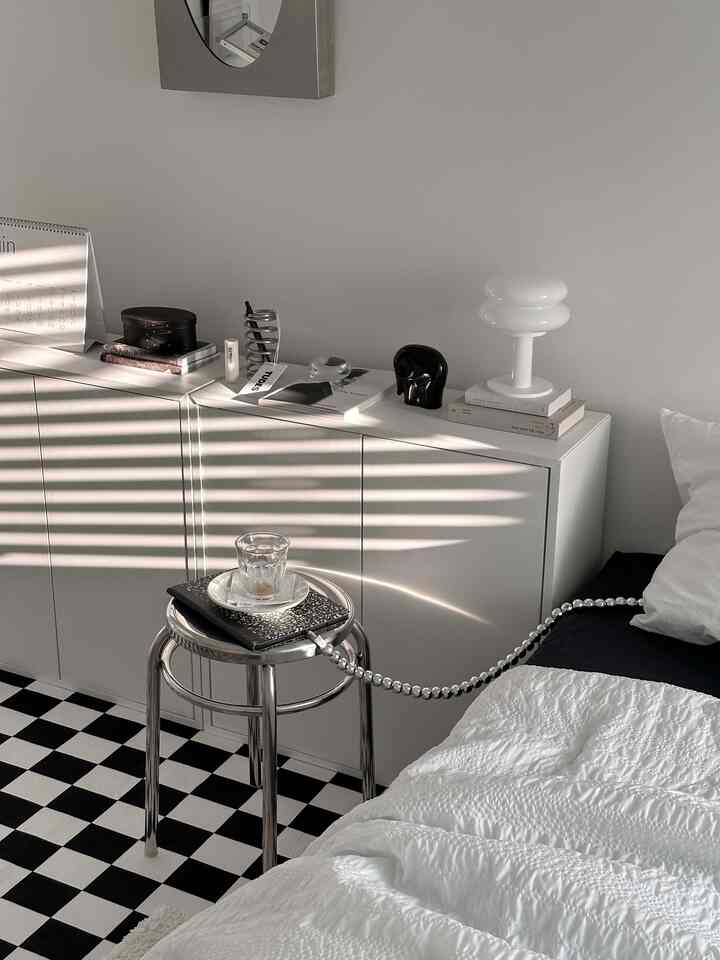 A white and black toned bedroom featuring a modern stool and sleek white cabinet for a simple and clean space