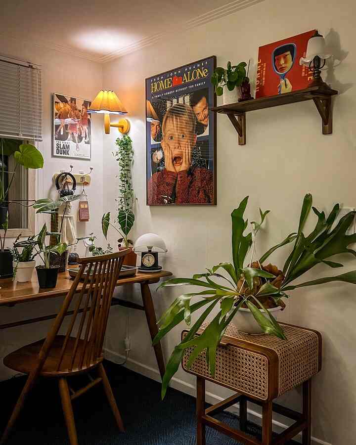 暖かい木目調とグリーンの植物が調和した書斎、ポスターと棚が印象的な雰囲気あるインテリア
