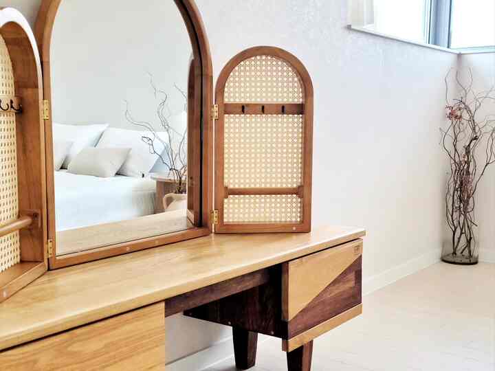 Wood tone and white bedroom vanity space featuring a large mirror with minimal and clean interior atmosphere