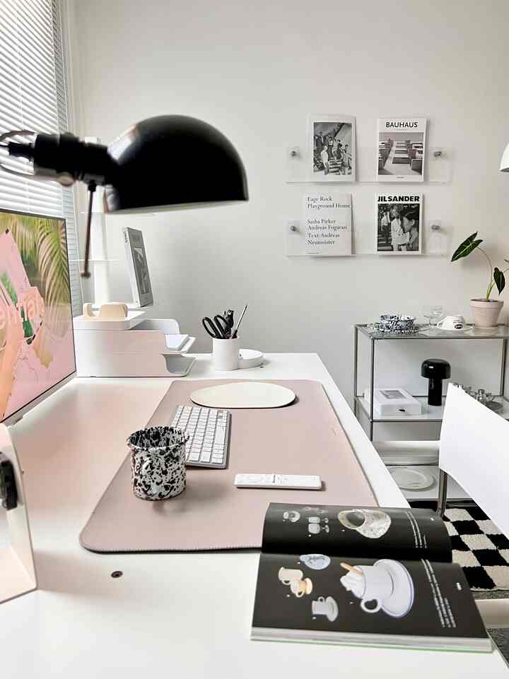 Simple modern home office in white and black tones featuring a desk and transparent wall shelves with a clean layout