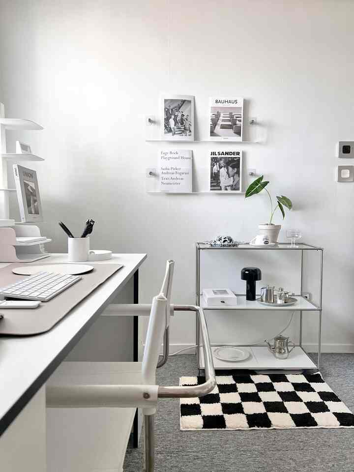 White and transparent toned study featuring mid-century modern armchair and shelves, creating a clean and modern atmosphere