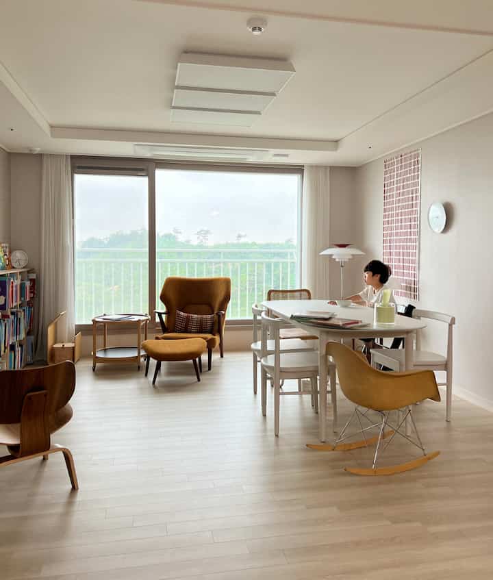 Bright white and brown toned living room featuring dining table and yellow armchair, a family-friendly space