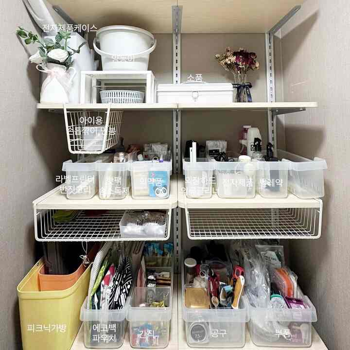 White-toned pantry space featuring neatly organized transparent plastic storage boxes and hanging baskets