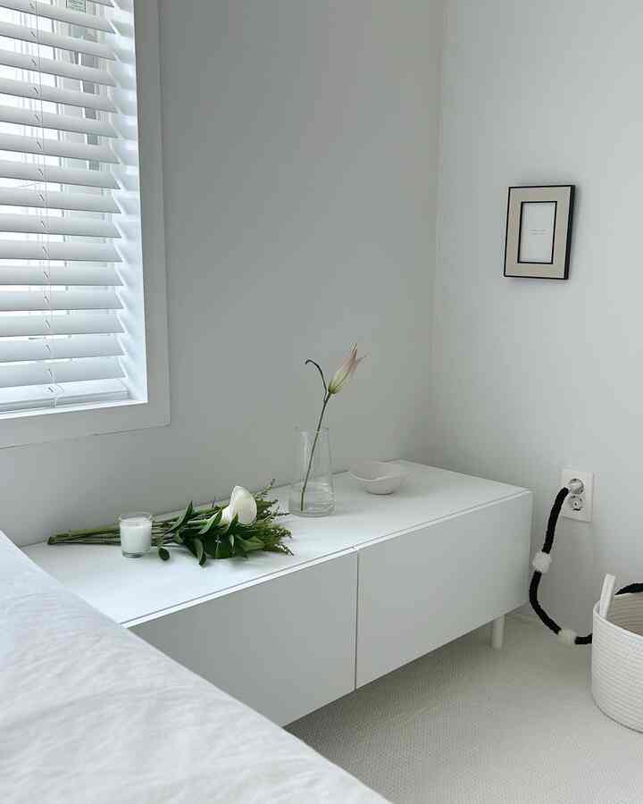 White and natural toned living room featuring a vase and candle on a minimalist cabinet