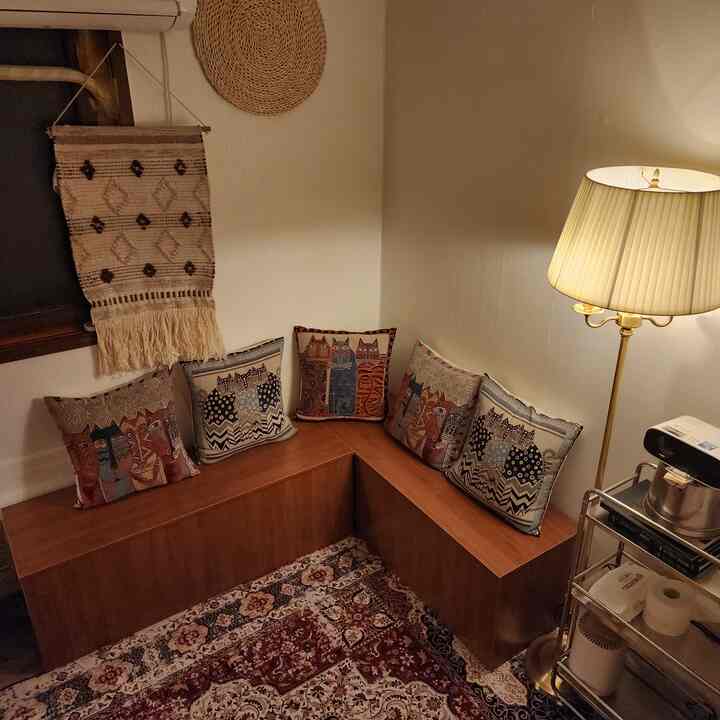 暖かみのあるブラウン調のコーナー収納ベンチとパターンラグがある居心地の良いダイニング、フロアランプが雰囲気を演出