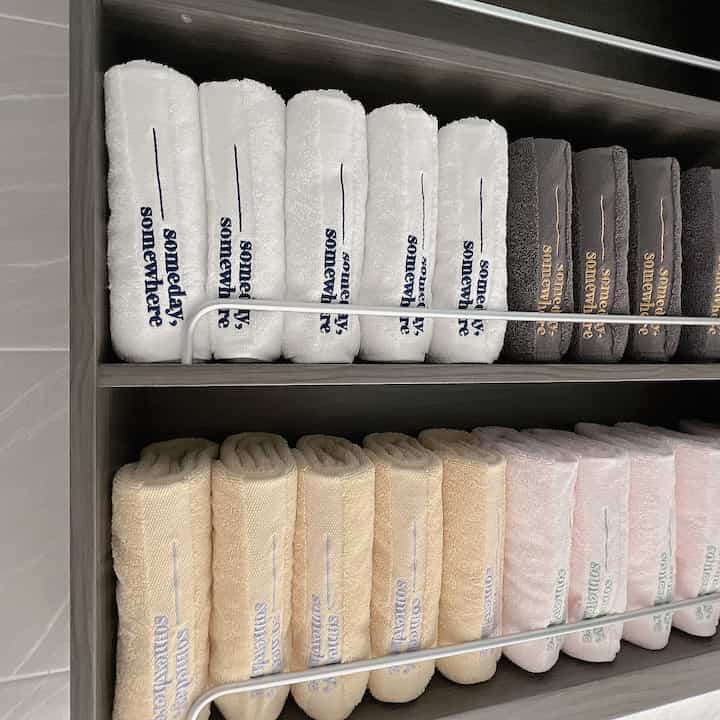 Bathroom storage featuring neatly arranged white, brown, and beige towels creating a natural and hotel-like feel