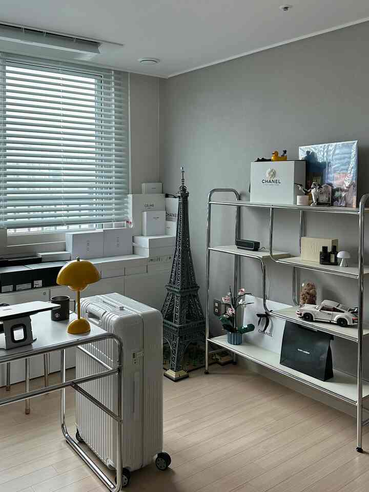 明るいホワイトとグレー調のワンルーム、メタルシェルフと窓ブラインドが配置された収納重視の清潔なインテリア