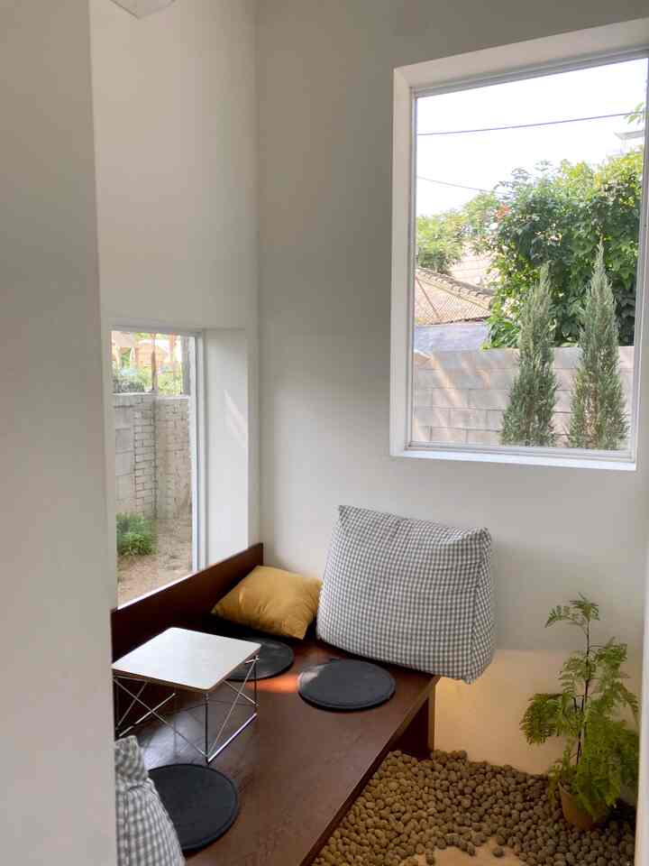 Light beige walls and wooden bench in a small old house cafe-style space, featuring natural elements and vintage cushions creating a cozy atmosphere
