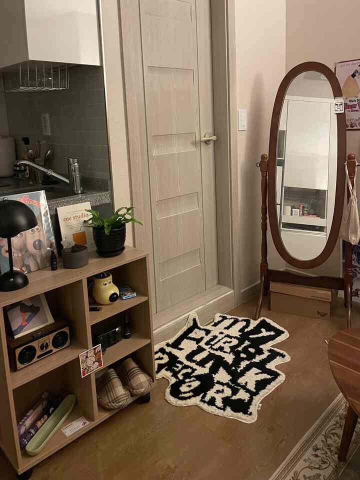 Entrance space with wood tones and natural vibe featuring a full-length mirror and patterned rug, creating a cozy interior