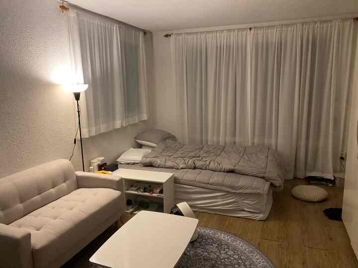 Cozy single household bedroom with beige sofa and bed against white walls