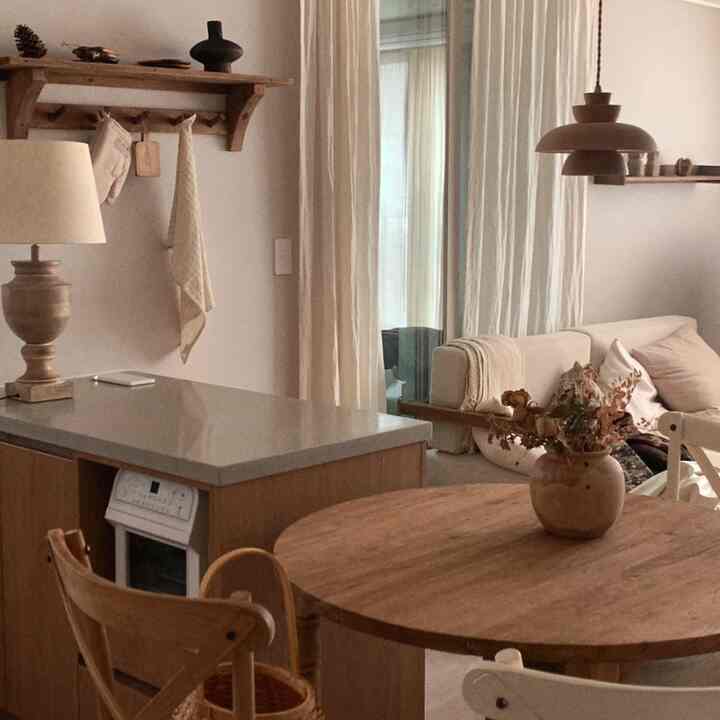 Natural color and wood tone kitchen-living space featuring wooden dining table and kitchen island with a cozy interior atmosphere