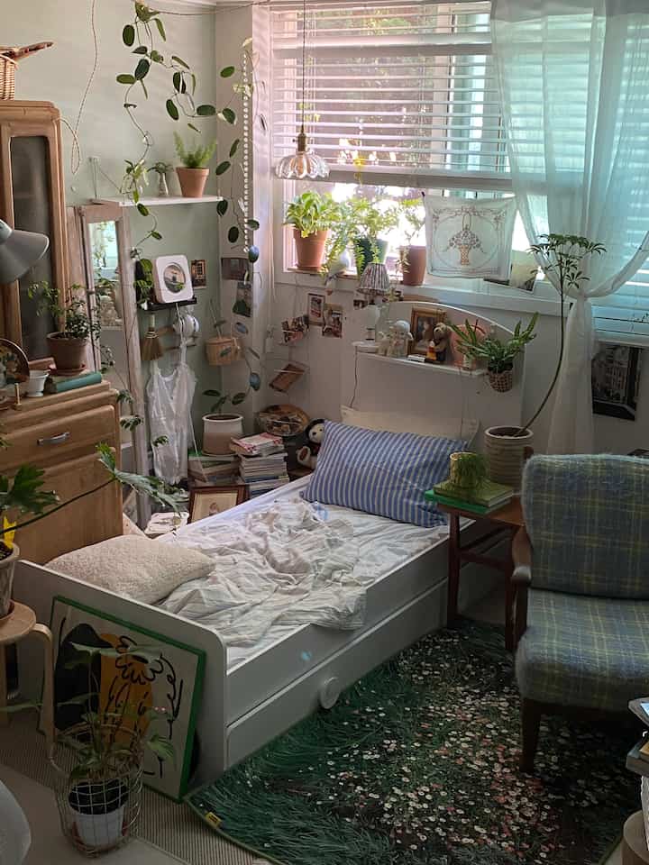 White and green wood-tone vintage style bedroom featuring plants and curtains creating a natural, cozy atmosphere