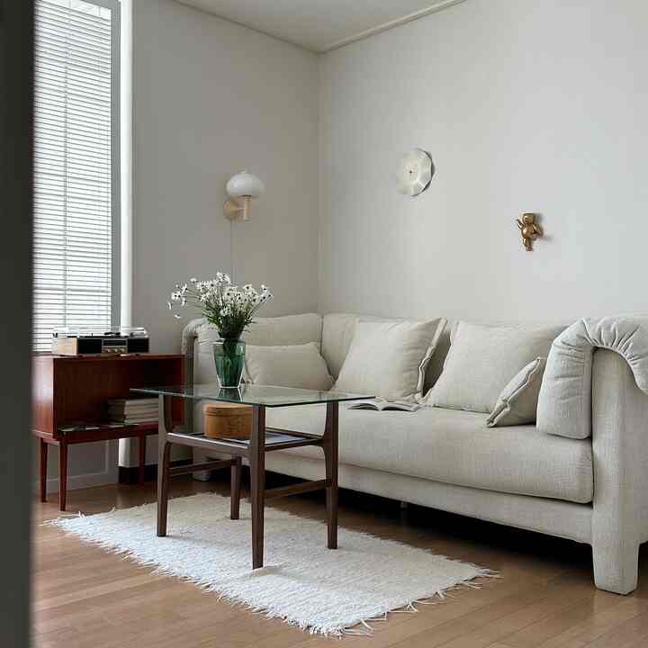 ホワイトとブラウンの色調の書斎、ベージュのソファとガラスのコーヒーテーブルが配置された自然で落ち着いた雰囲気のインテリア