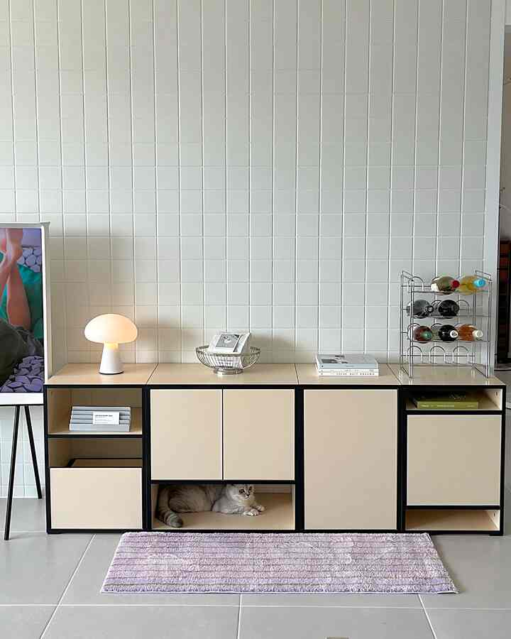 白いタイル壁とナチュラルカラーのサイドボード、テーブルランプやワインラック、猫がいる落ち着いた印象の空間