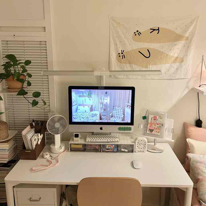 Modern home office in white and beige tones featuring a computer and desk arranged tidily with a cozy atmosphere