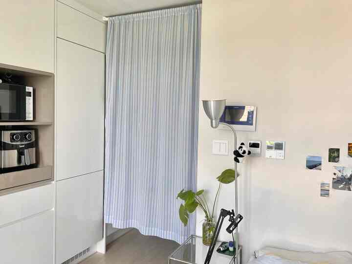 Minimal bedroom with white and blue tones featuring striped curtains and simple furniture