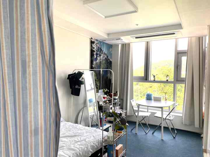 A cozy 6-pyeong studio with white walls and blue flooring, featuring a transparent room divider and simple furnishings in the bedroom and dining area