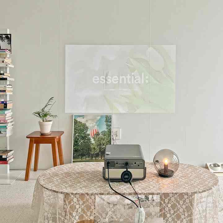 White and beige toned living room featuring a ViewSonic 4K projector and round table with glass table lamp in a simple modern setting