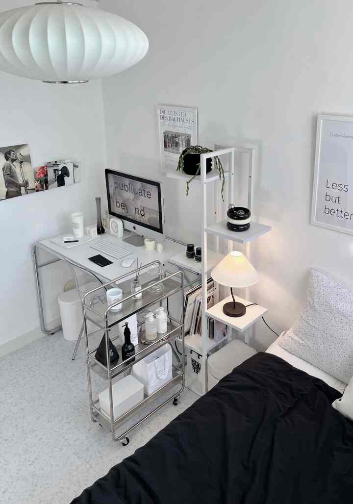 白と黒のトーンの寝室、コンピュータデスクとベッド、ペンダントライトが配置されたモダンな空間