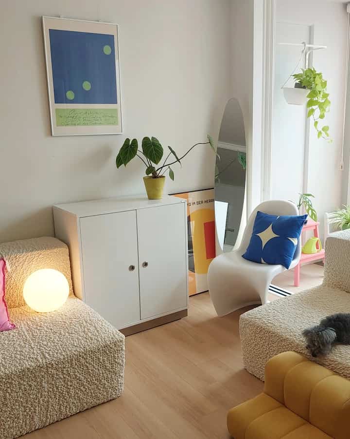Natural living room with white walls and wood tone floor featuring beige sofas and plants in a modern setting