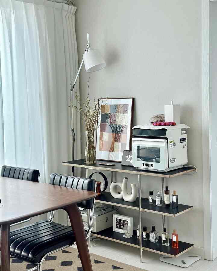 Modern living room with white walls and curtains background, featuring a black shelf, wooden dining table, and dining chairs