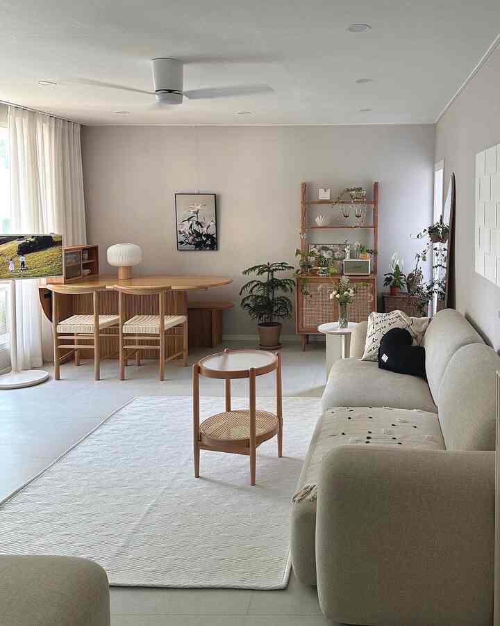Ivory and natural wood tone living room featuring wooden furniture and rattan side table, creating a clean and cozy home cafe interior