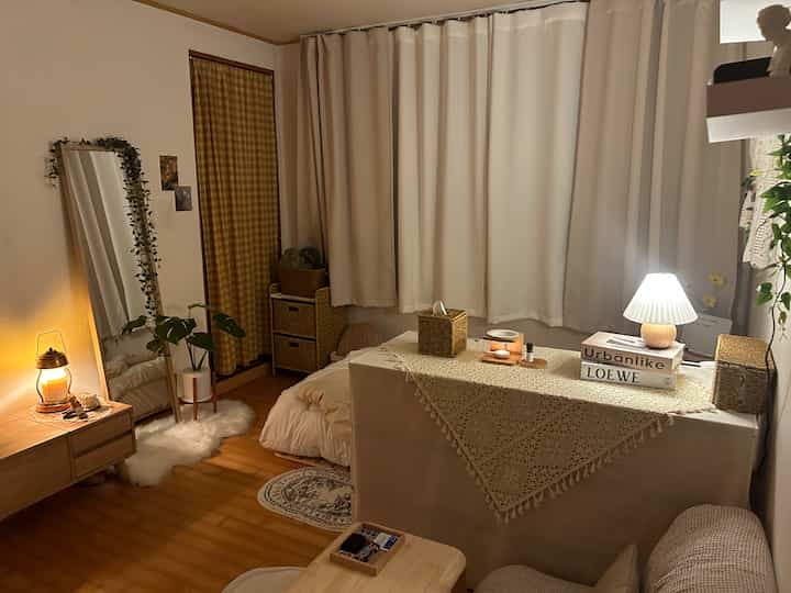 Beige-toned bedroom featuring natural wood flooring, storage solutions, rug and ambient lighting creating a cozy atmosphere