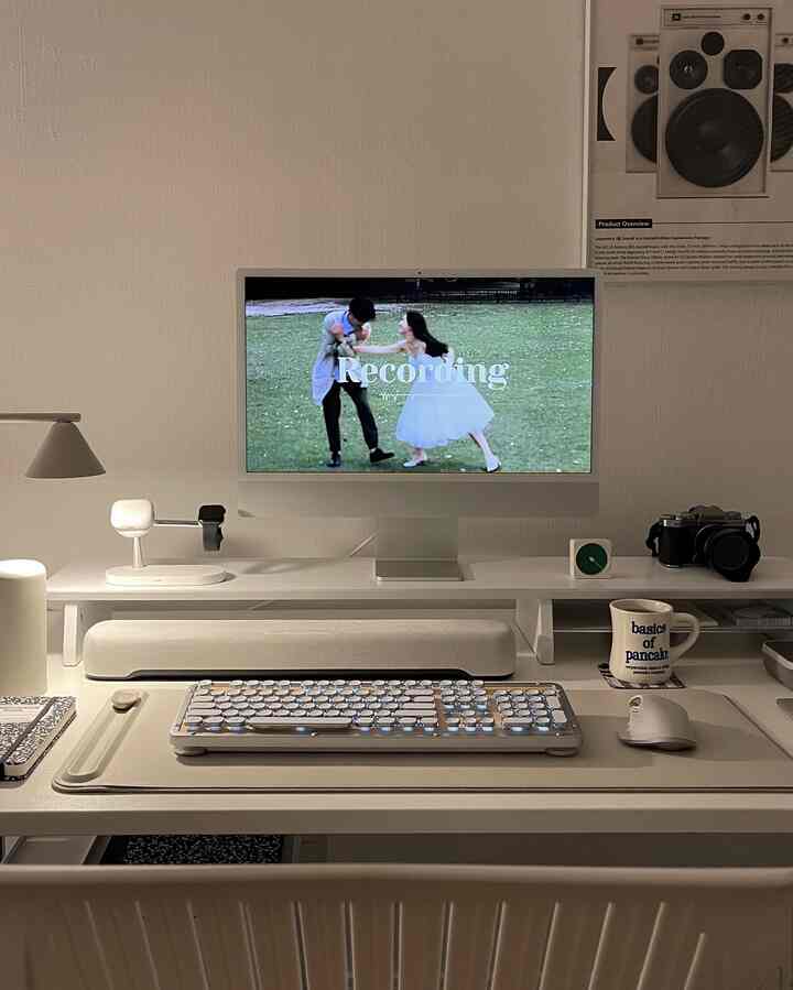 White and gray toned home office featuring iMac and minimalistic desk with assorted items in a sleek workspace