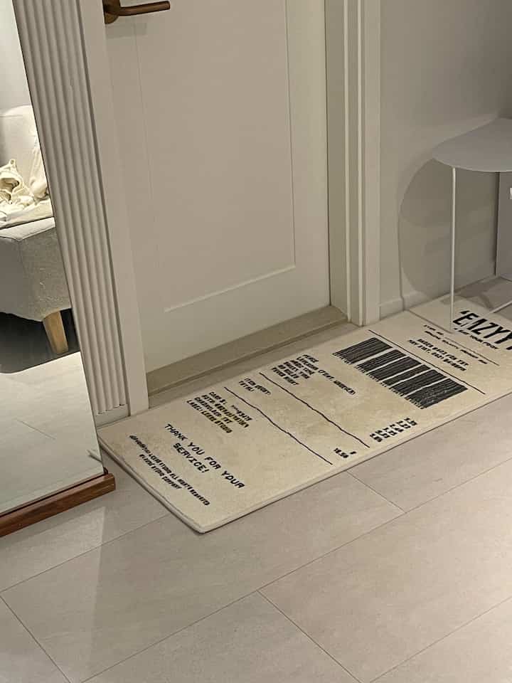 薄いベージュ色のバスルーム入口に配置されたレシートデザインの長いバスマット