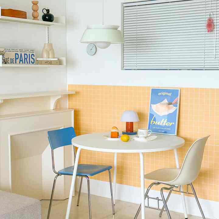 ホワイトとイエローのタイル壁が特徴的な、ミッドセンチュリーモダンスタイルの明るい2人用ダイニングルーム