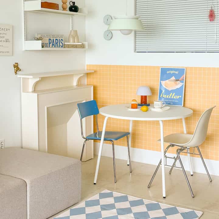 A simple and cozy home cafe space featuring a round white table and chairs against white and yellow tiled walls