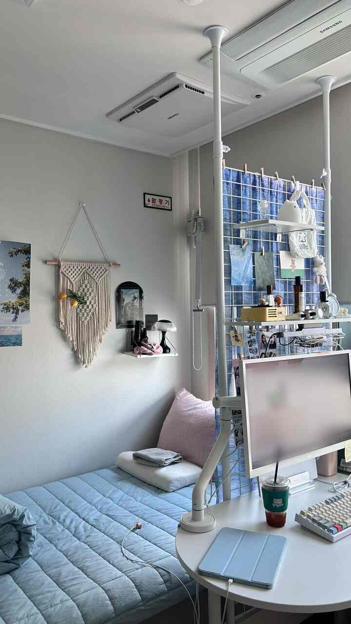 ホワイトとスカイブルーのトーンの狭い寝室、ベッドとホームオフィス用のモニター付きデスクが配置された空間