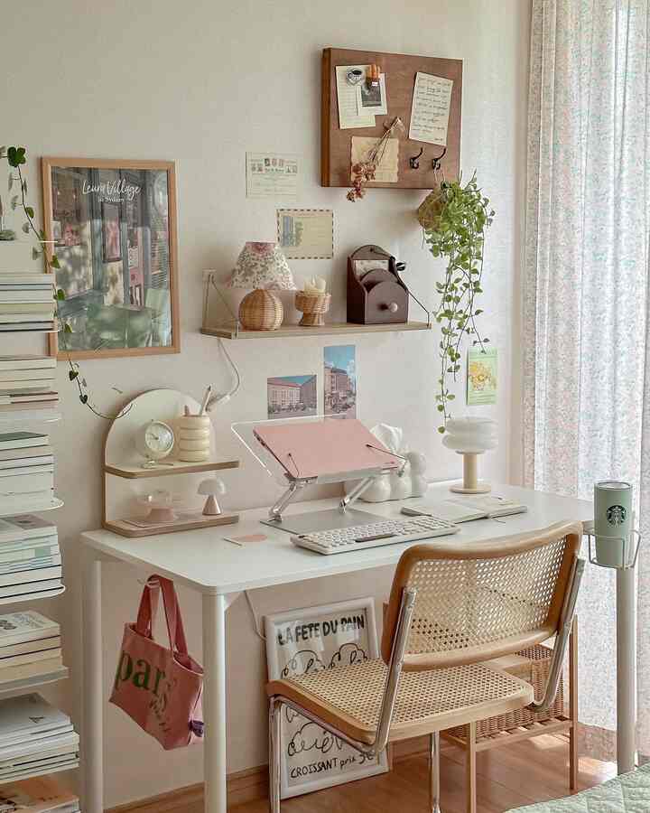 ナチュラルカラーの寝室デスクゾーン、ラタンチェアと壁面の多彩な額装が印象的な空間