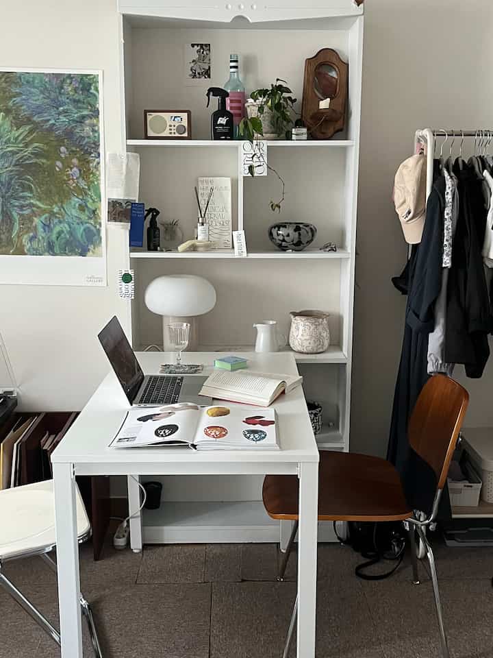 Compact single household home office in white and brown tones, featuring a rectangular desk with wooden chair, bookshelf, and table lamp for practical study space