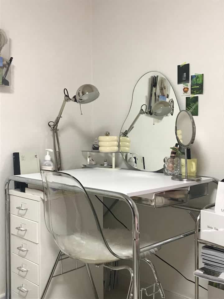 White and silver toned small home office featuring a transparent chair and lamps on a simple desk