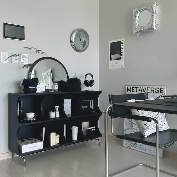 Modern living room in gray tones featuring black furniture, mirrors, and decorative accessories with a stylish atmosphere