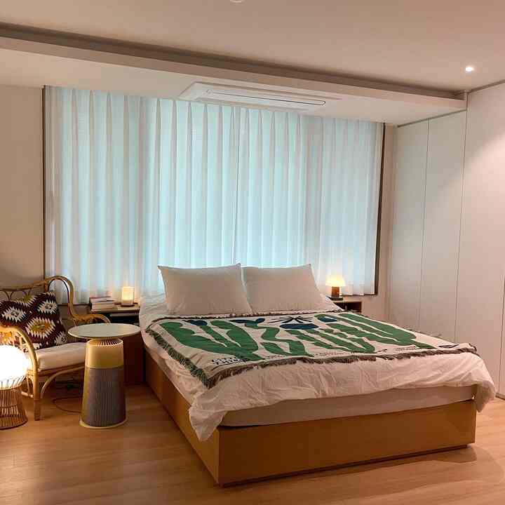 White and wood tone bedroom featuring bed, curtains, and table lamps creating a cozy atmosphere
