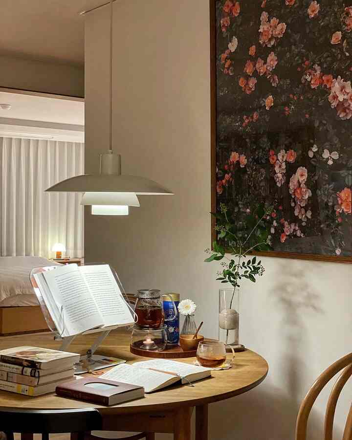 白い壁とナチュラルな木目調のテーブルがある落ち着いたダイニングルーム、読書とティーセットが印象的な雰囲気のあるインテリア