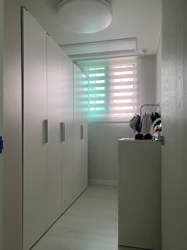 白を基調とした狭いウォークインクローゼット、ハンセムのワードローブとイケアのチェストが配置された実用的なインテリア