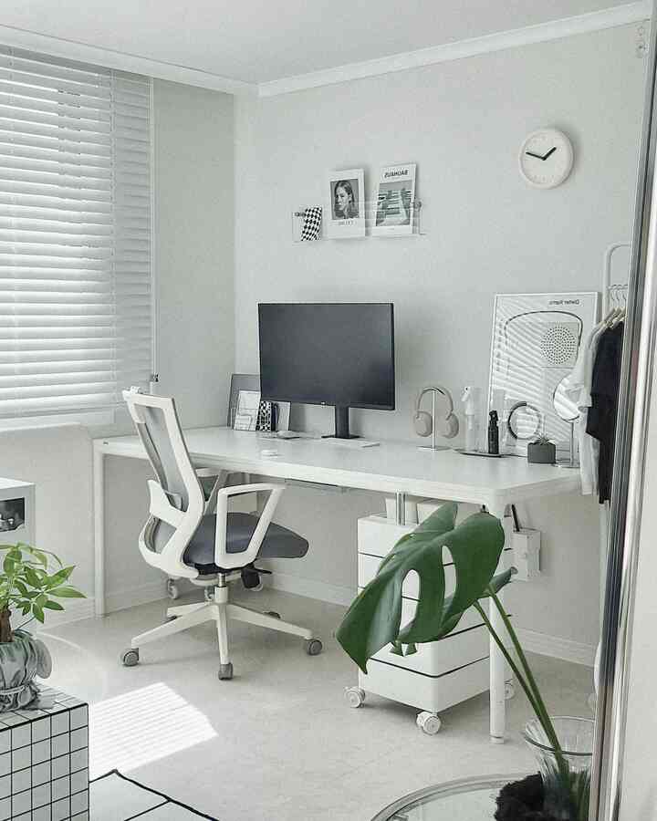 白を基調としたモダンなホームオフィス、デスクや椅子、壁時計や棚、植物が配置された印象的な空間