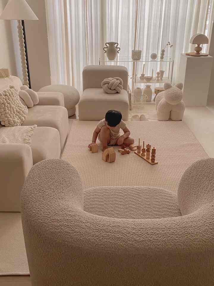 ベージュの色調のリビングルーム、木製のおもちゃで遊ぶ赤ちゃんがいる雰囲気のある空間