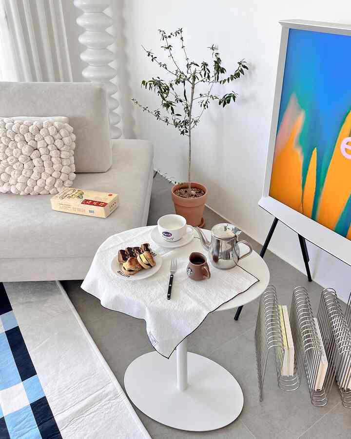 White and wood tone studio living room featuring sofa and home cafe setup on round table with a cozy atmosphere