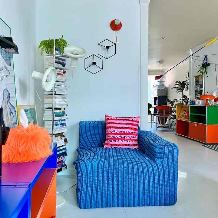 Bright white-toned living room featuring a blue sofa with pink cushion and colorful modular furniture in a modern setup